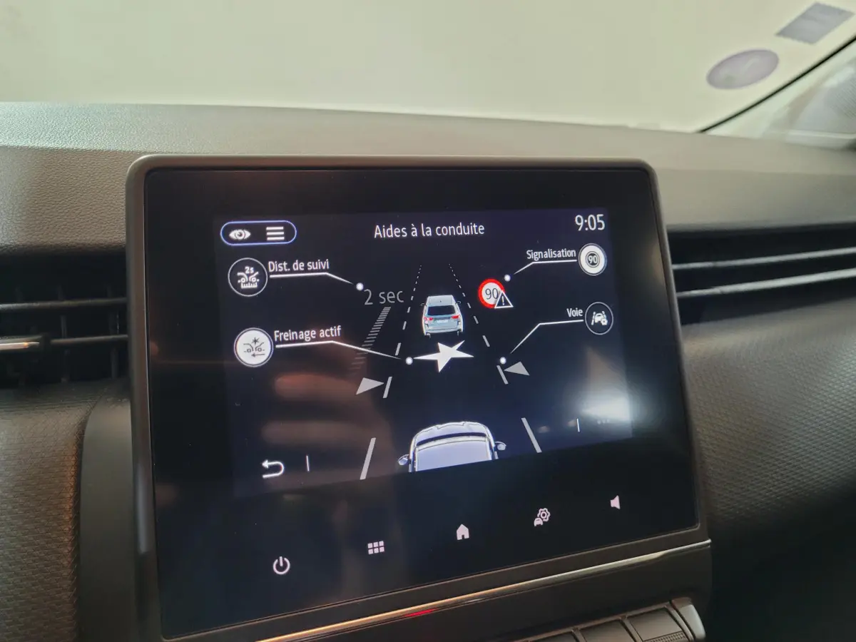 Écran tactile central montrant les aides à la conduite dans l'habitacle d'une Renault Clio Business blanche.