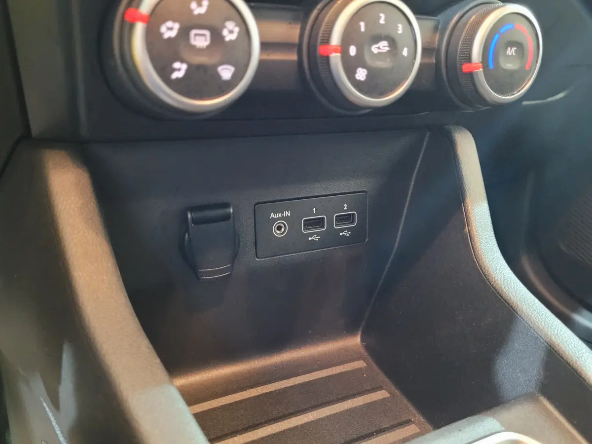 Gros plan sur la console centrale noire de la Renault Clio Business avec commandes climatisation et ports USB visibles.