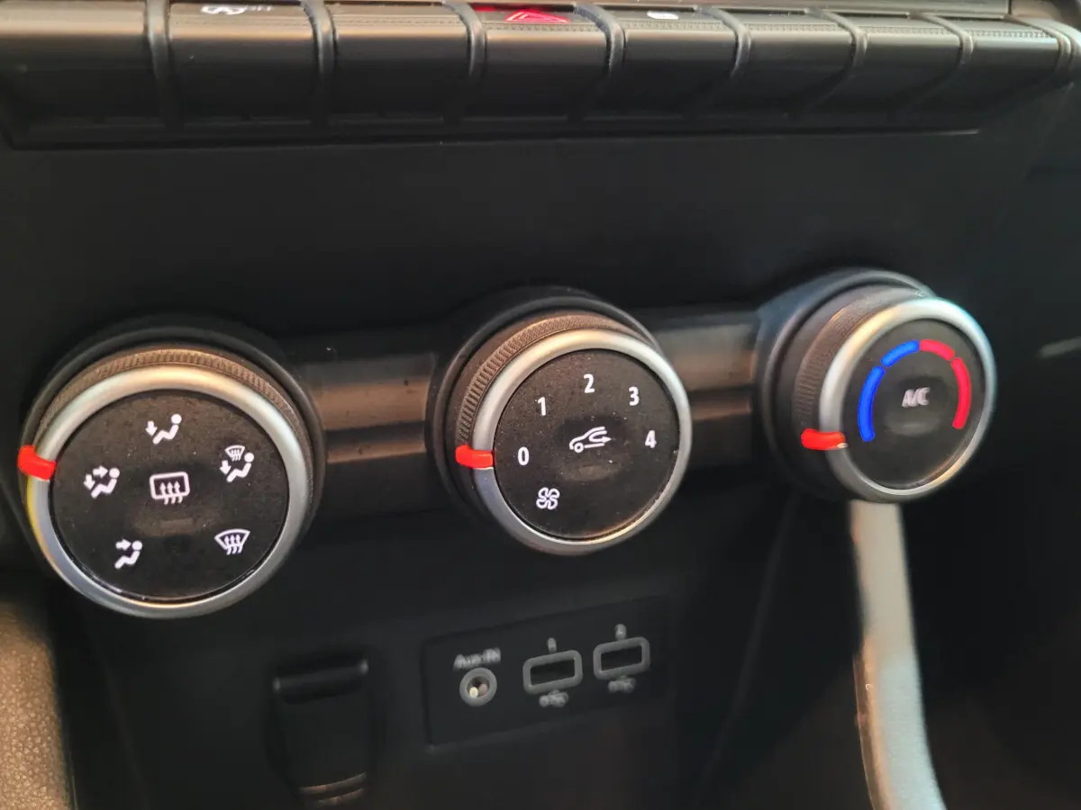 Gros plan sur les commandes de climatisation de la Renault Clio Business blanche, avec réglages ventilation et température.