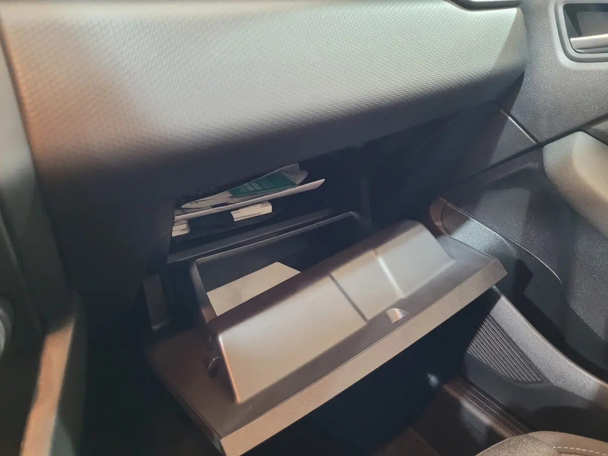 Gros plan sur la boîte à gants ouverte côté passager de la Renault Clio Business blanche, montrant des documents à l'intérieur.