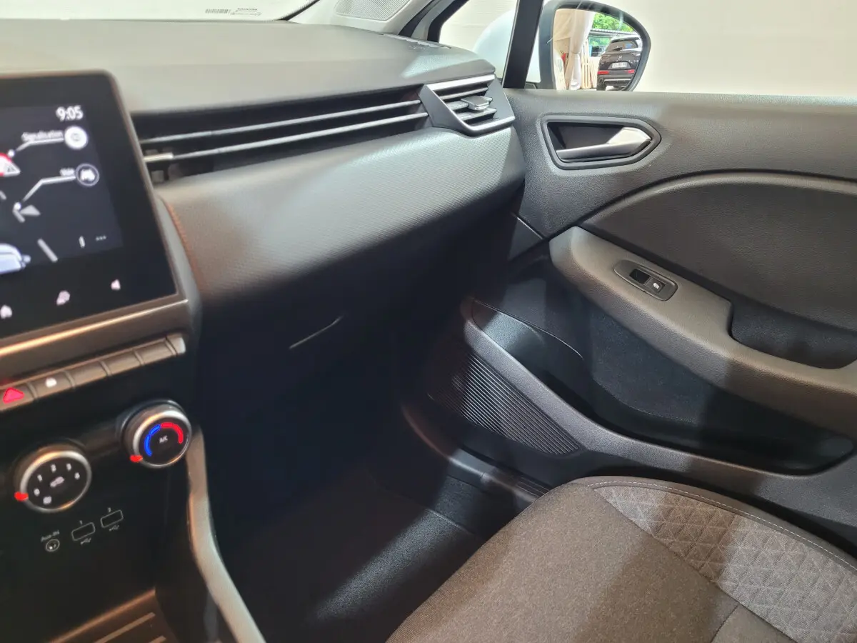 Vue intérieure côté passager de la Renault Clio Business blanche 2021, avec tableau de bord et commandes climatisation visibles.