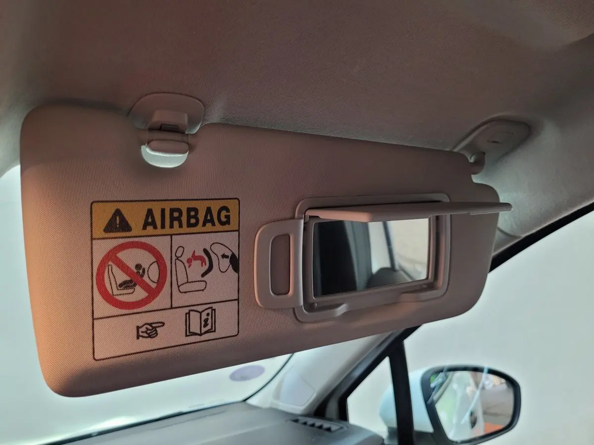 Détail du pare-soleil côté conducteur avec miroir et avertissement airbag dans l'habitacle d'une Renault Clio blanche.