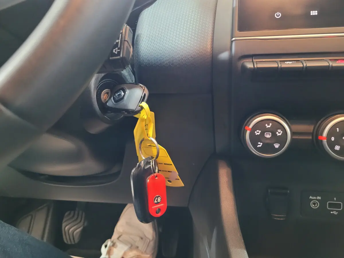 Gros plan intérieur sur le contacteur avec clé insérée et commandes de climatisation d'une Renault Clio Business blanche.