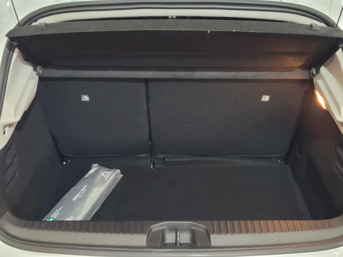 Coffre ouvert de la Renault Clio Business blanc, vue de l'arrière montrant un espace de chargement vide avec un kit de sécurité.