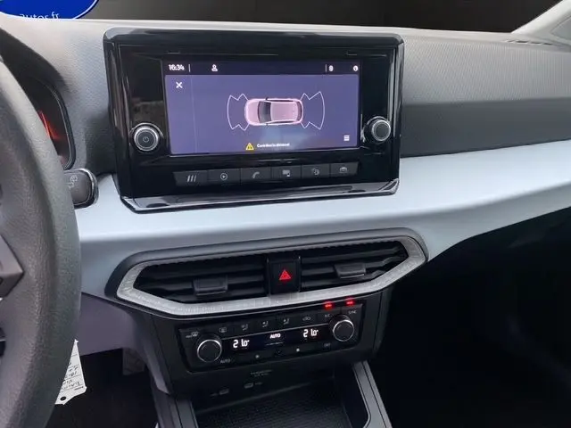 Tableau de bord blanc et noir de la SEAT Ibiza 2023 avec écran tactile affichant l'aide au stationnement.