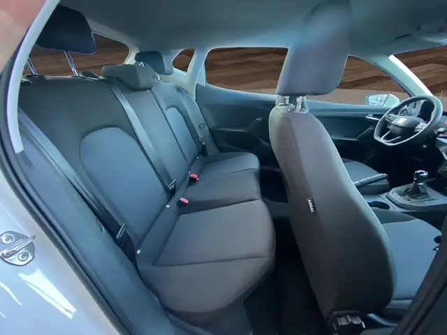 Intérieur de la SEAT Ibiza 2023 blanc candy, vue côté gauche montrant les sièges arrière et avant en tissu gris.