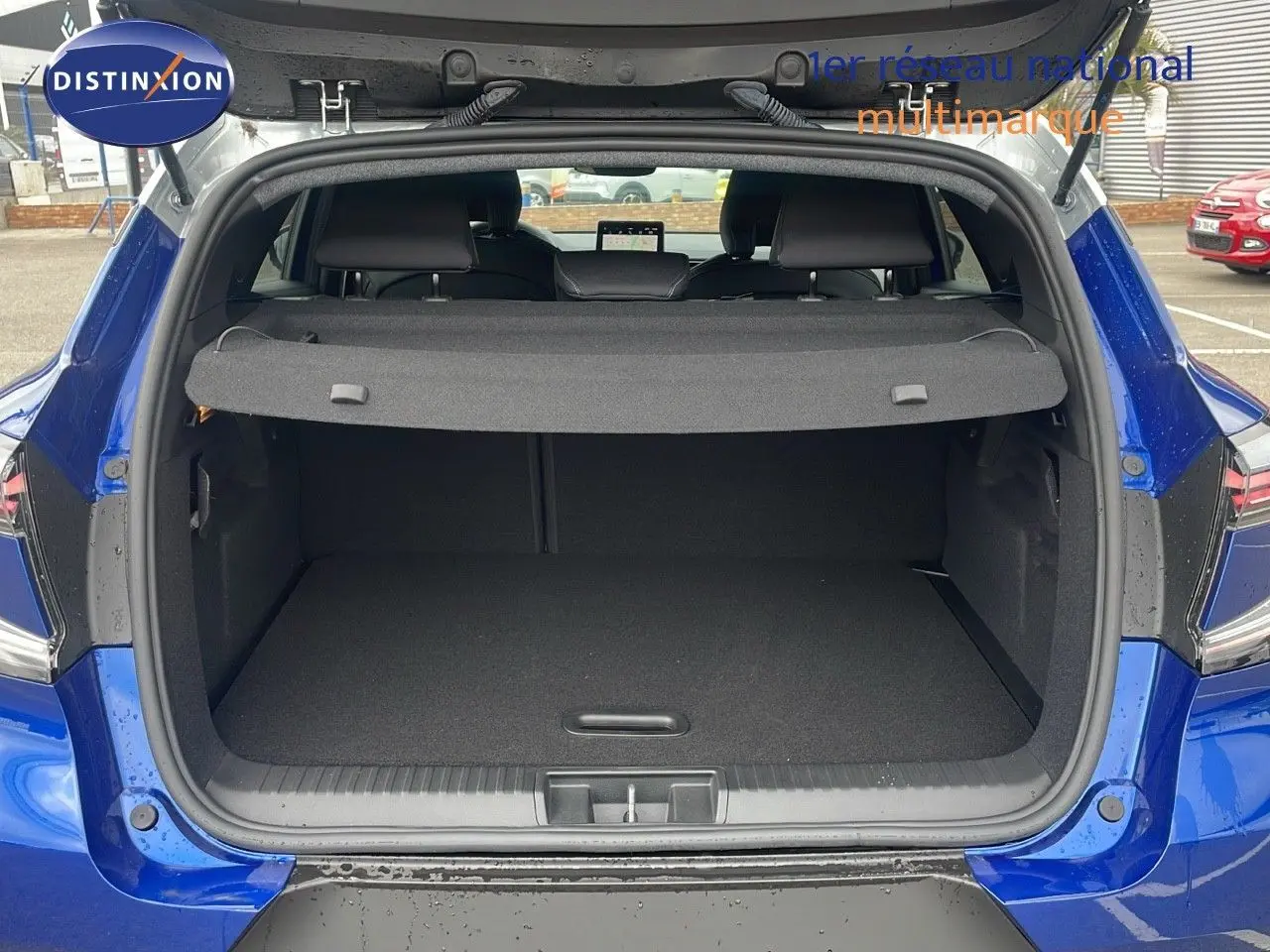 Coffre ouvert d'un Renault Captur E-Tech hybride 2025 bleu Iron Metal avec toit gris, vue arrière extérieure.