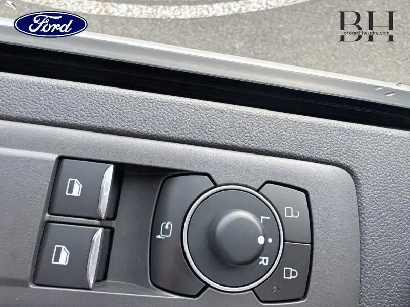 Gros plan sur les commandes des rétroviseurs et vitres du Ford Transit Custom gris lunaire métallisé, intérieur cabine.