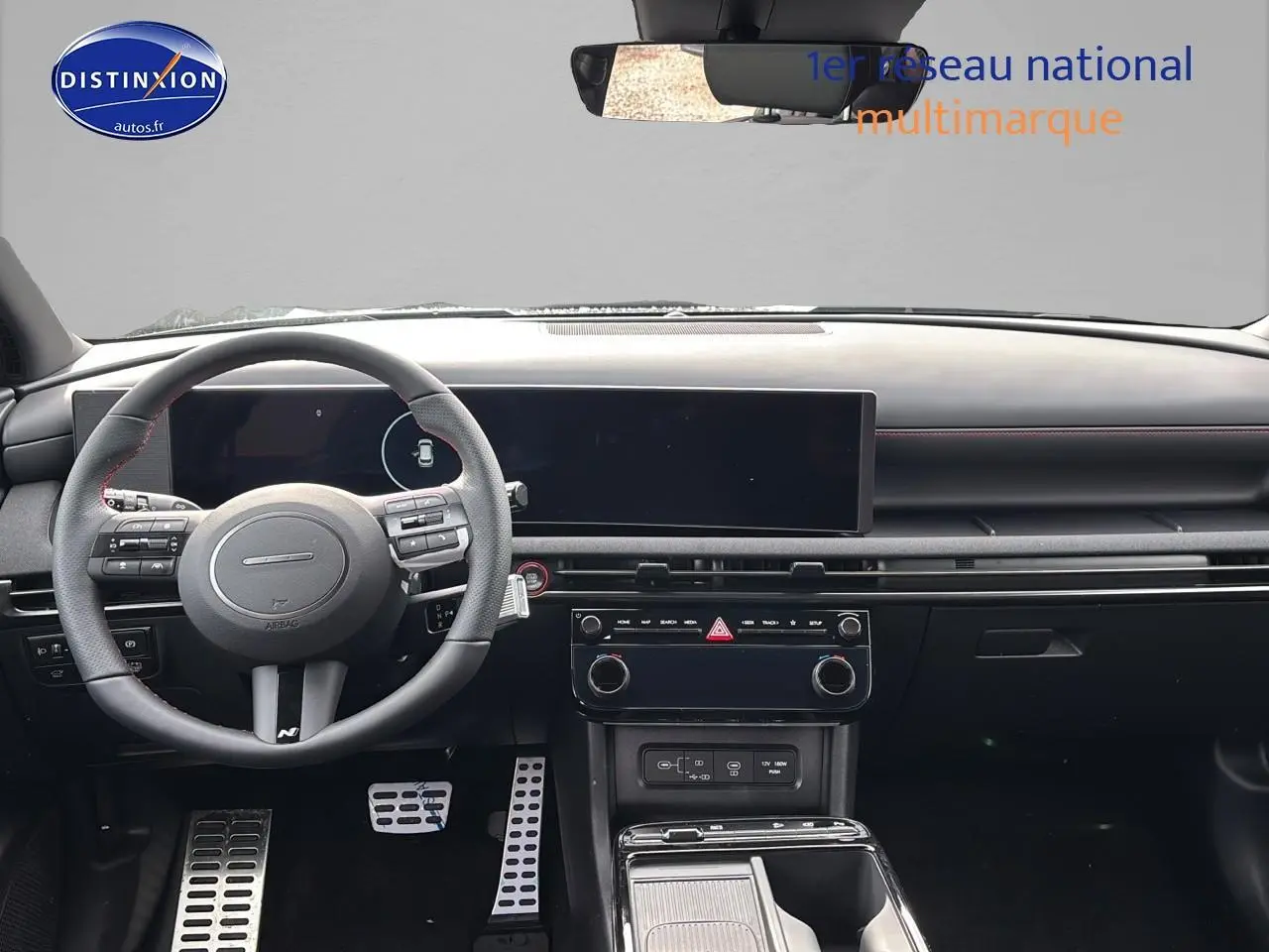 Vue intérieure avant du Hyundai Tucson 2026 gris Shadow, volant cuir multifonction avec surpiqûres rouges et écran tactile large.