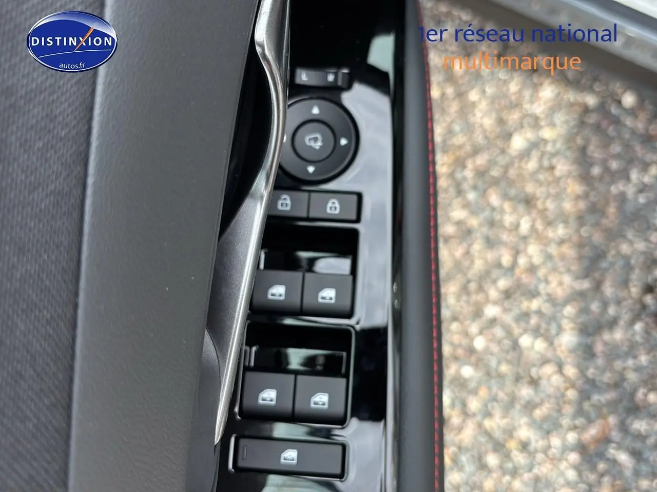 Gros plan sur la commande des vitres électriques côté conducteur du Hyundai Tucson gris Shadow, avec surpiqûres rouges visibles.