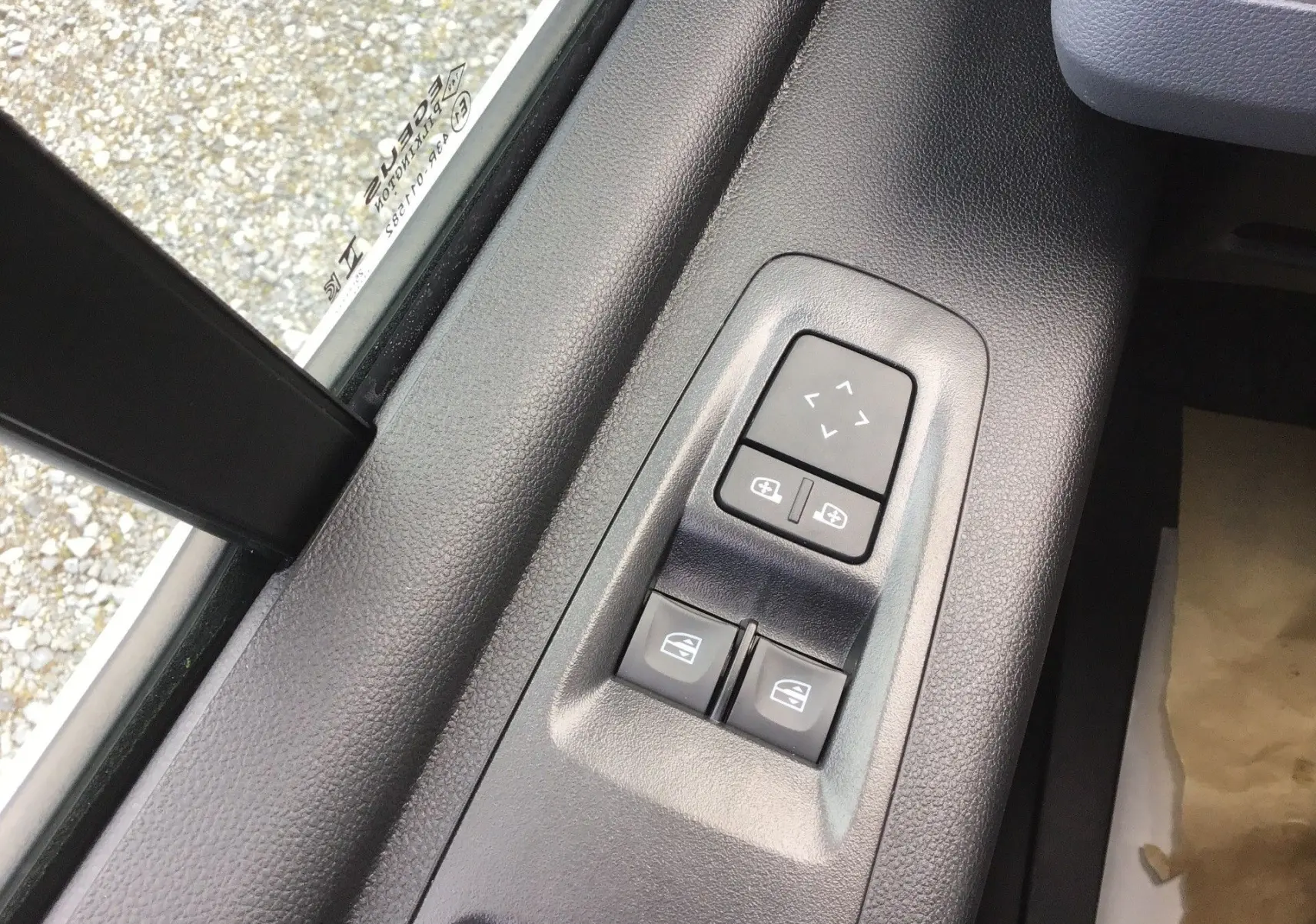 Gros plan sur les commandes électriques des vitres et rétroviseurs côté conducteur du Renault Master blanc, intérieur noir.