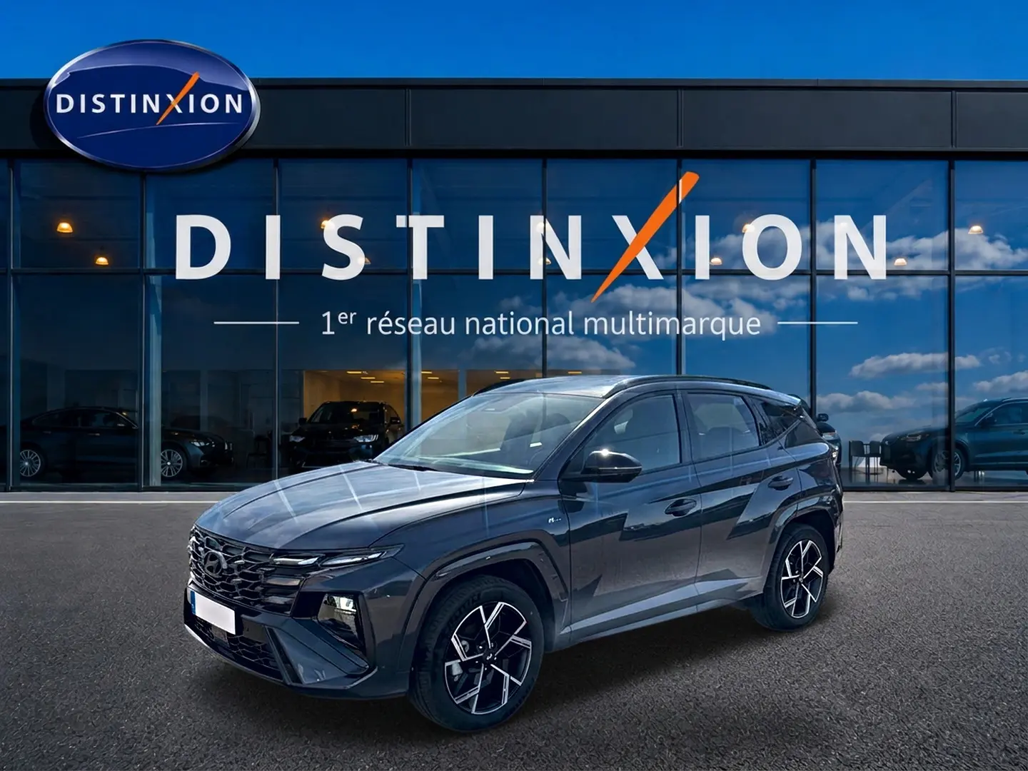 Hyundai Tucson 2026 gris ecotronique en 3/4 avant droit, avec calandre glossy black et jantes alliage 19 pouces.