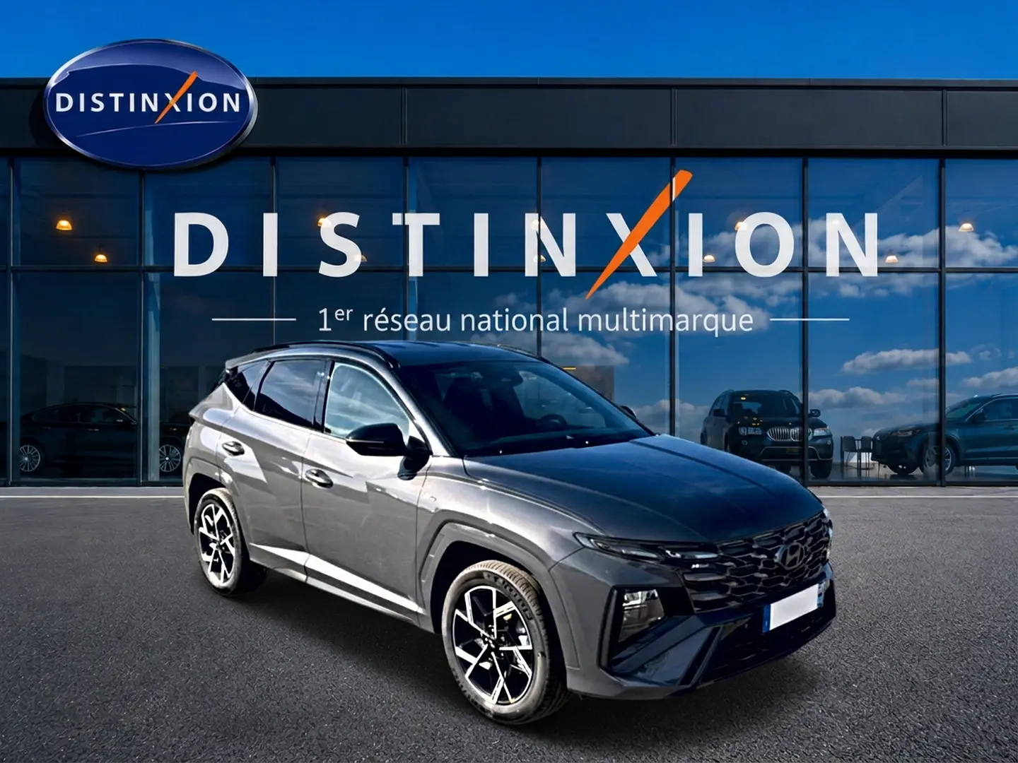 Hyundai Tucson gris écotronique en 3/4 avant droit, avec calandre glossy black et jantes alliage 19 pouces.
