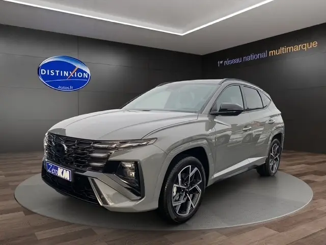 Vue 3/4 avant d’un Hyundai Tucson gris foncé 2026 avec jantes alliage et calandre distinctive N Line en showroom.