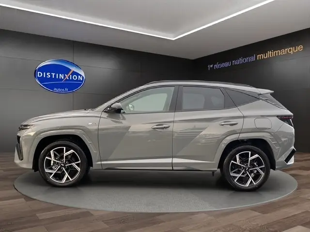 Vue de profil côté gauche du Hyundai Tucson 1.6 Hybrid gris foncé avec jantes alliage et toit noir en showroom.