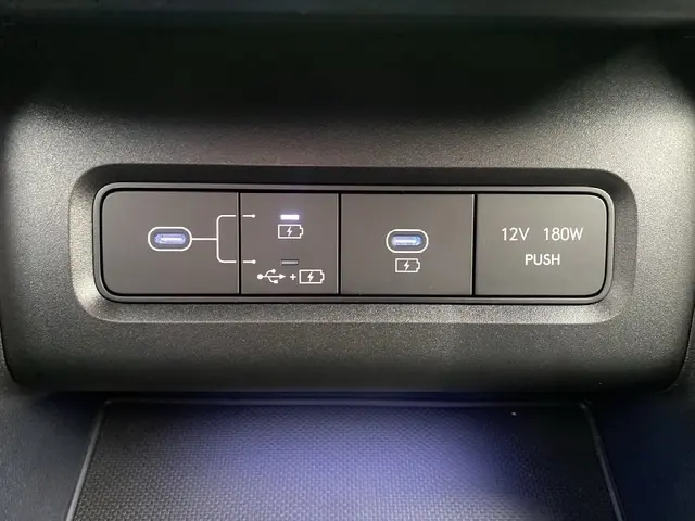 Gros plan sur la console intérieure du Hyundai Tucson 2026 gris foncé, montrant les ports USB et prise 12V avec éclairage bleu.