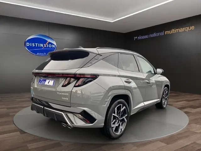 Vue 3/4 arrière droite du Hyundai Tucson 1.6 Hybrid N Line Creative gris foncé avec hayon motorisé en showroom.