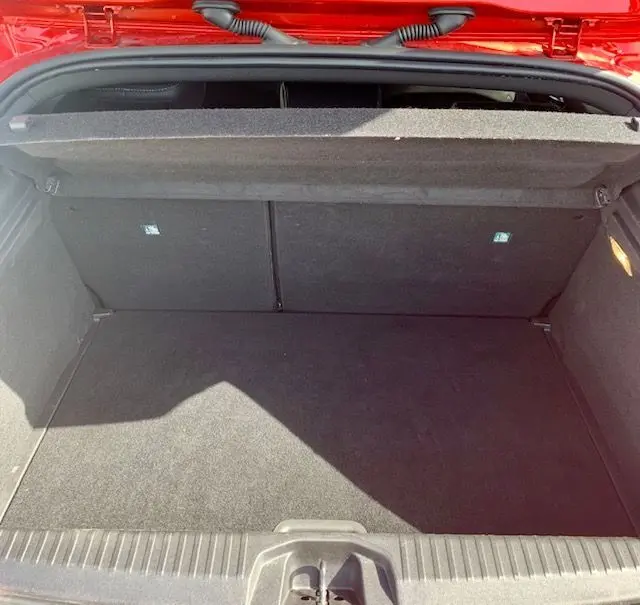 Coffre ouvert vu de l'arrière d'une Renault Clio V rouge 2021, montrant un espace de chargement propre et vide.