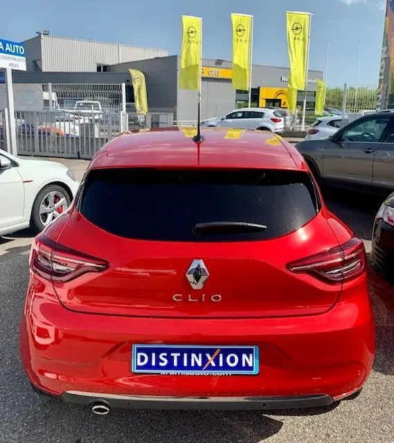 Vue arrière d'une Renault Clio V rouge 2021 avec vitres teintées et plaque d'immatriculation Distinxion visible.