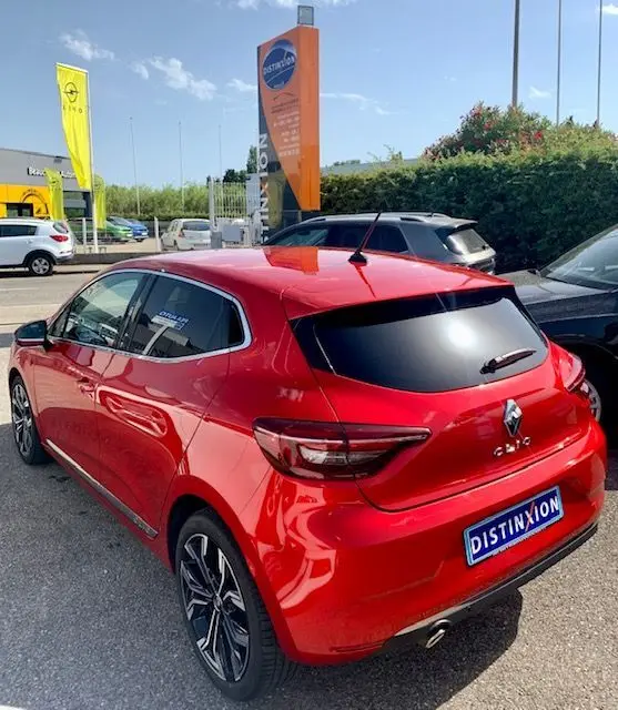 Vue 3/4 arrière droite d'une Renault Clio V rouge 2021 avec vitres teintées et jantes alliage distinctives