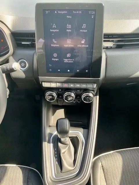 Vue rapprochée de la console centrale de la Renault Clio V rouge 2021, avec écran tactile et levier de boîte automatique.