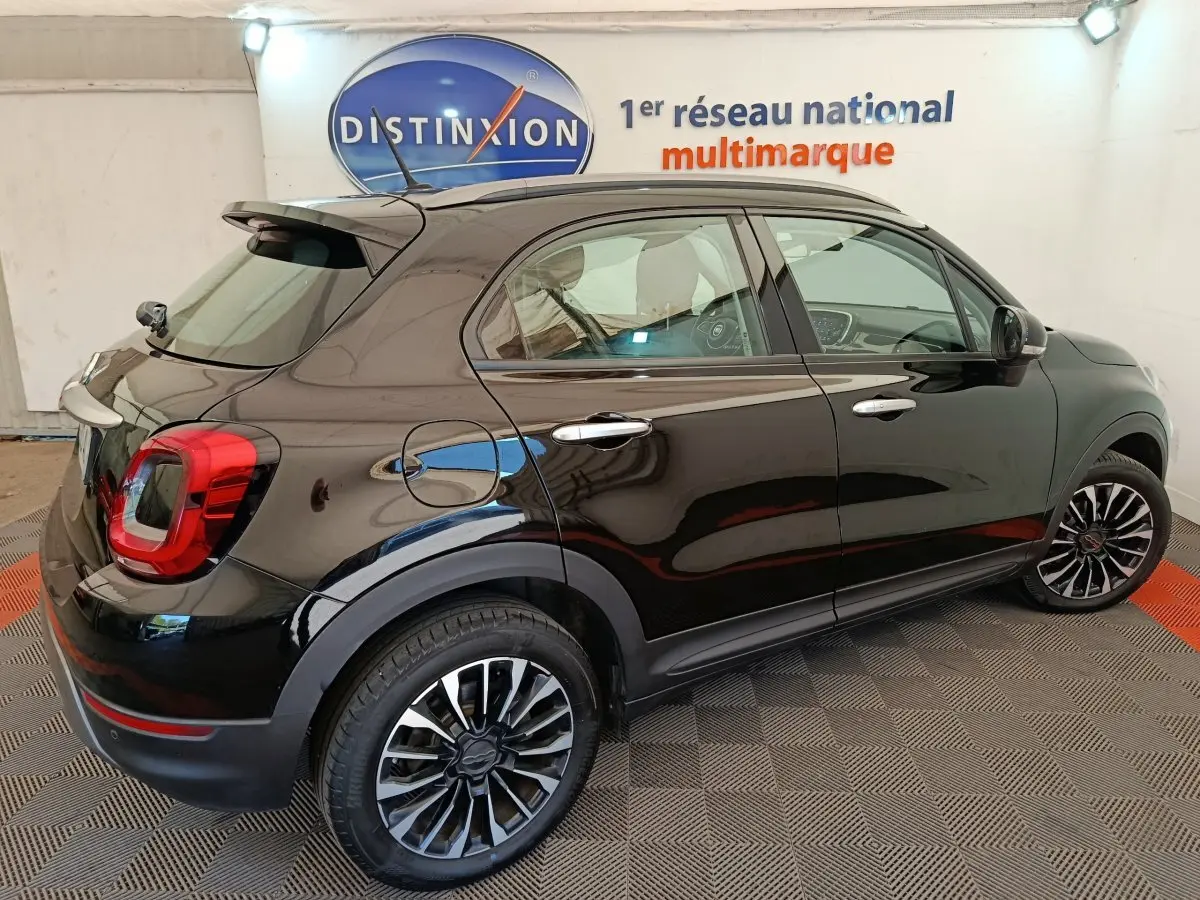 Vue 3/4 arrière droite d'un FIAT 500X noir avec jantes alliage et feux arrière LED dans un showroom.