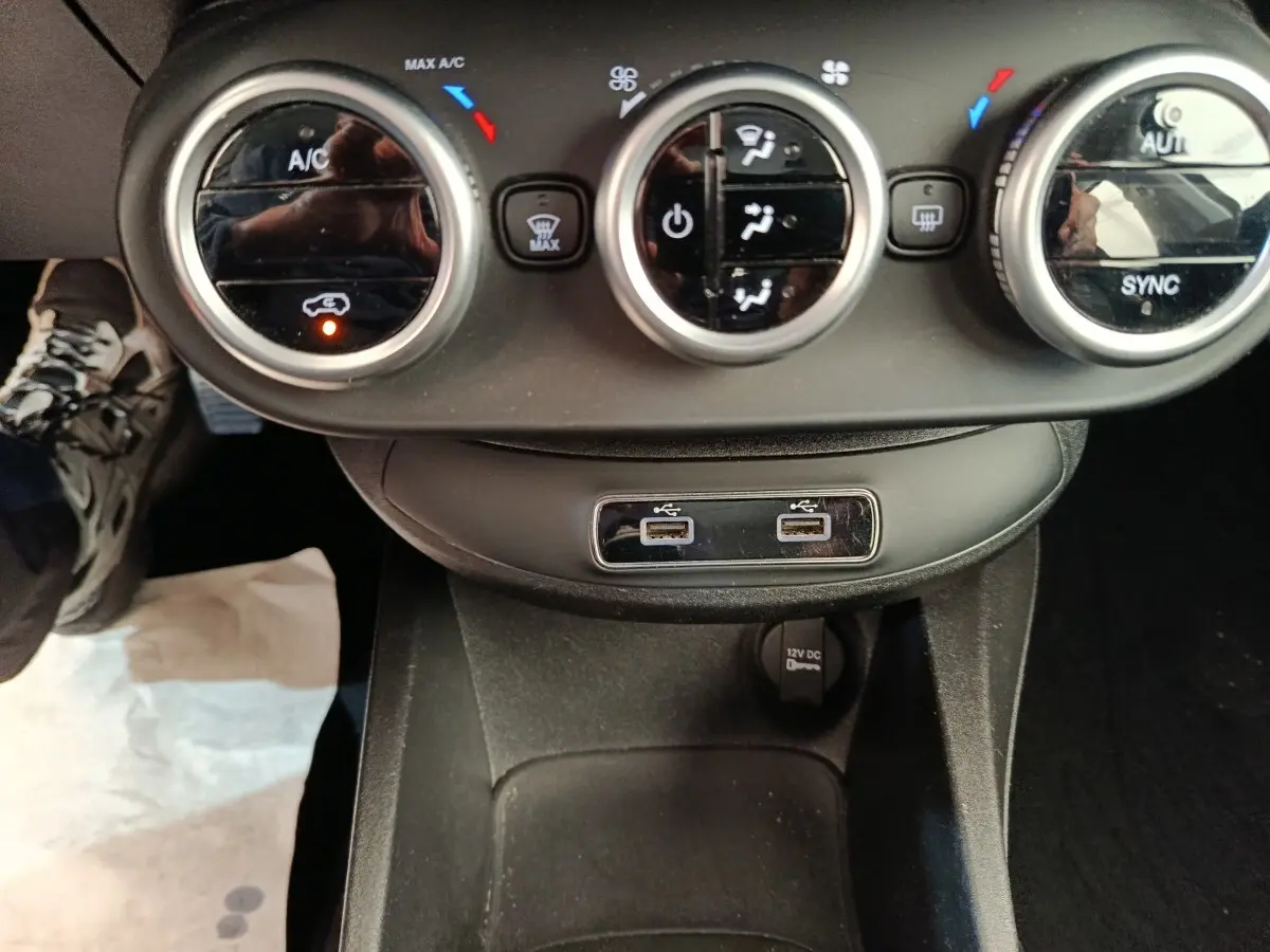 Vue rapprochée du tableau de bord central de la Fiat 500X blanc, montrant les commandes de climatisation et ports USB.