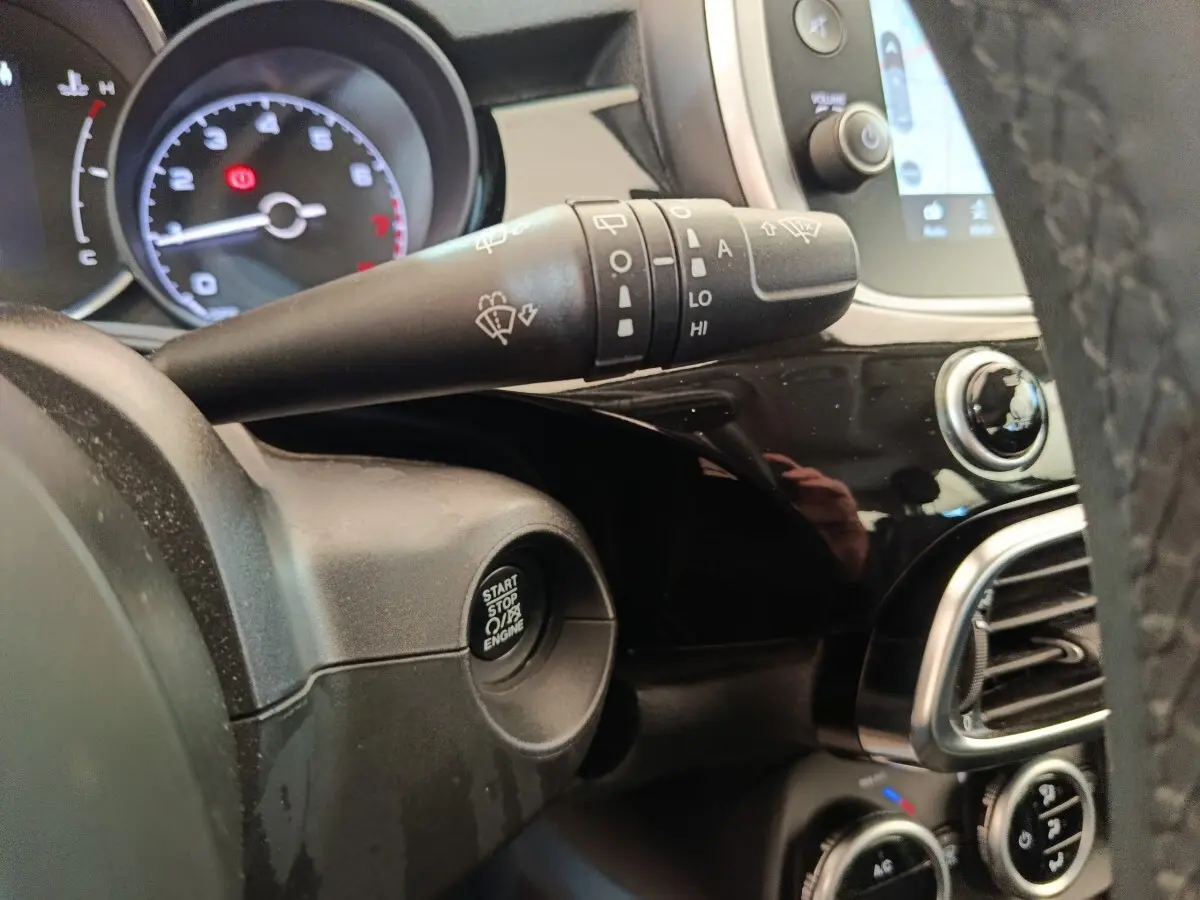Gros plan intérieur sur le tableau de bord noir de la Fiat 500X, avec bouton start/stop et commande essuie-glace.