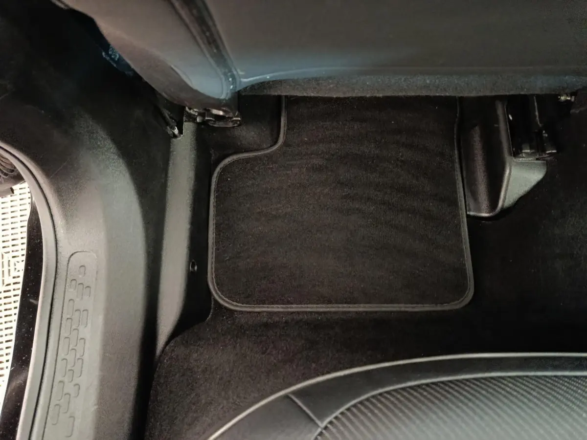 Détail du tapis de sol noir côté passager arrière du Fiat 500X blanc, intérieur sobre et propre.