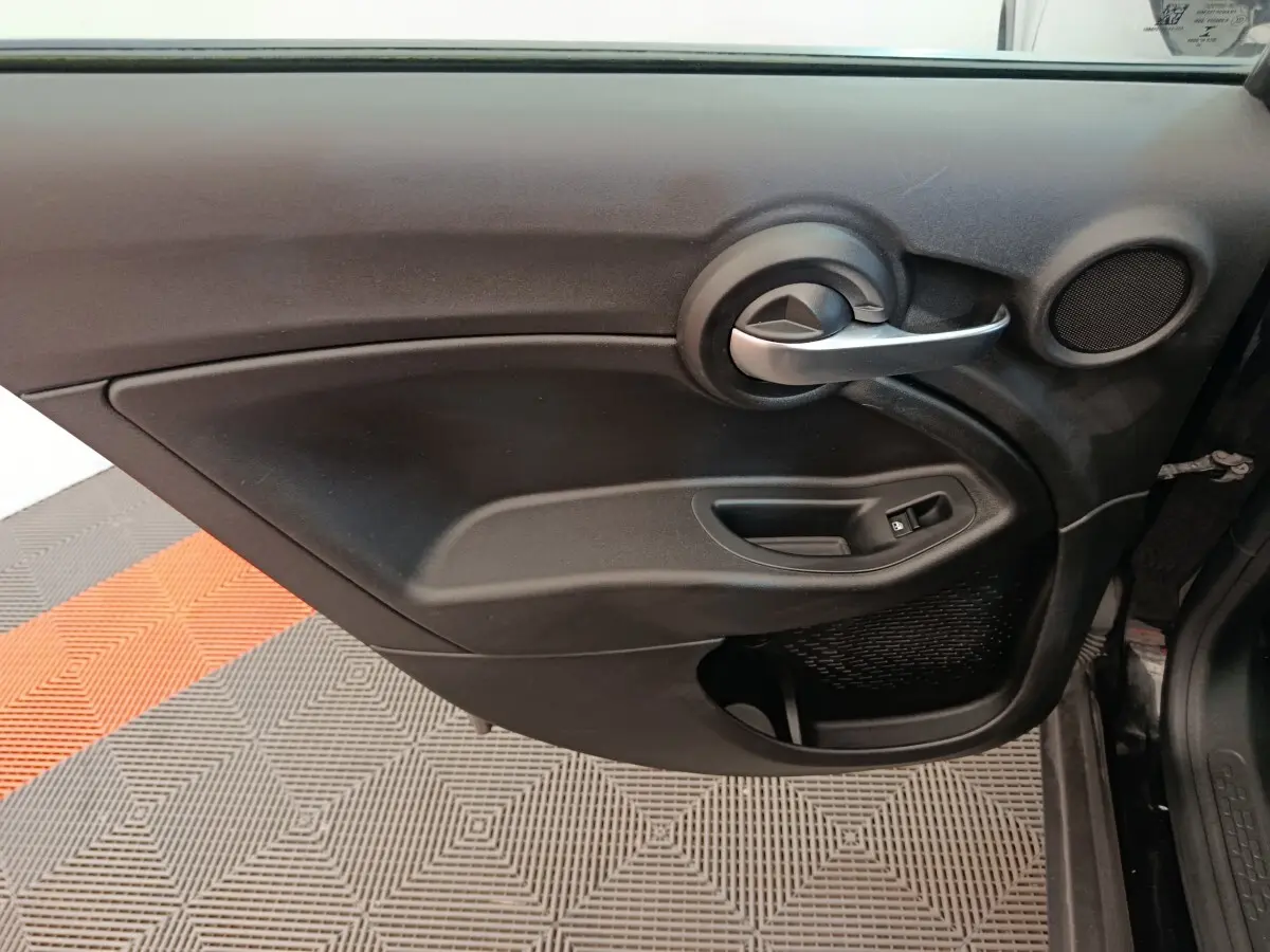 Gros plan sur la porte intérieure côté conducteur noire du Fiat 500X 2020 avec poignée argentée et commande de vitre électrique.