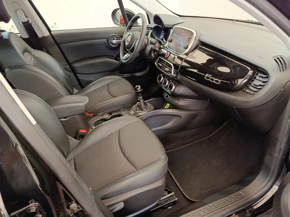 Intérieur noir de la FIAT 500X 2020 vu côté conducteur, tableau de bord brillant avec logo 500 et écran tactile central.