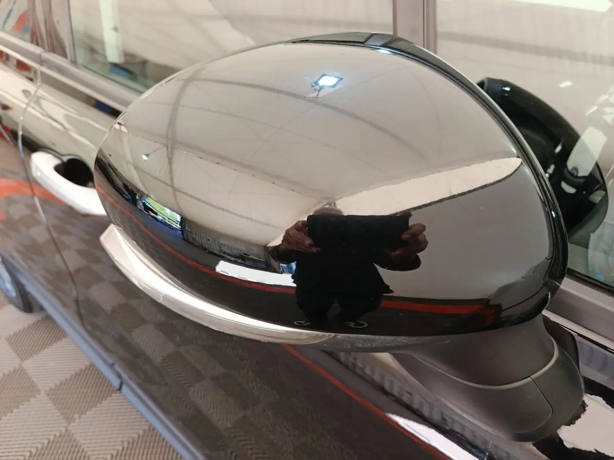 Rétroviseur extérieur noir brillant côté conducteur d'une FIAT 500X 2020, reflet de l'environnement intérieur visible.