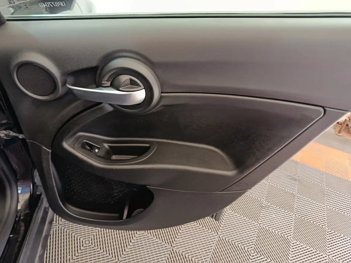Intérieur côté droit de porte FIAT 500X blanc, avec poignée argentée et commande de vitre noire.