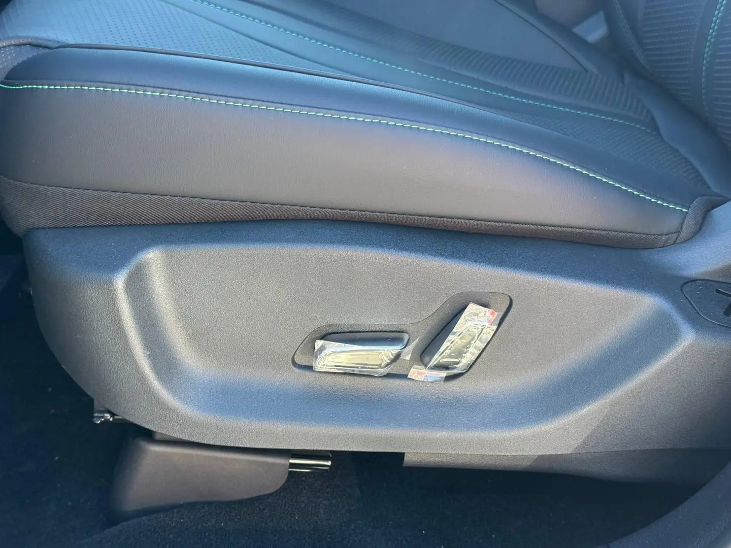 Gros plan sur les commandes électriques du siège avant noir avec surpiqûres vertes du BYD SEAL U 1.5 DM-i 2026.