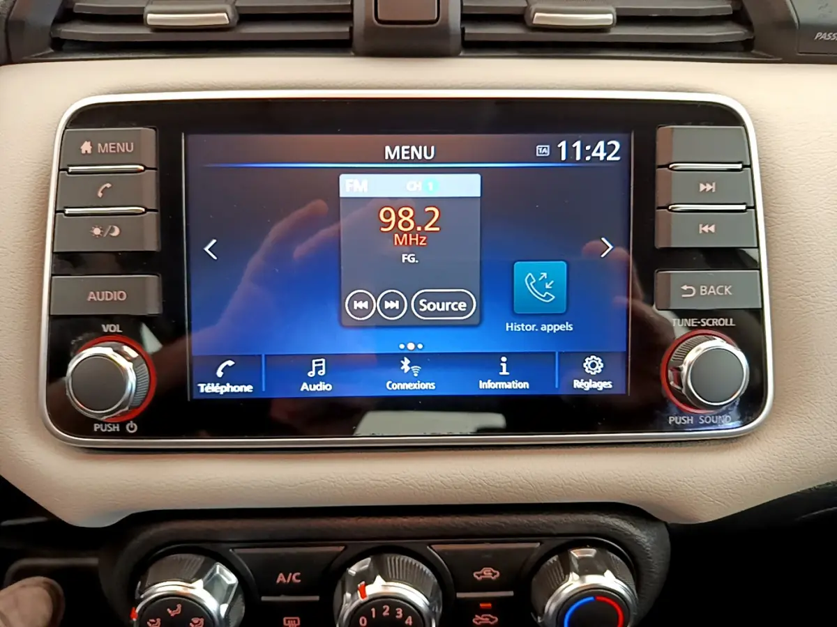 Écran tactile central de la Nissan Micra IG-T 92 Acenta 2022, affichant la radio FM, entouré de commandes audio et climatisation beige.