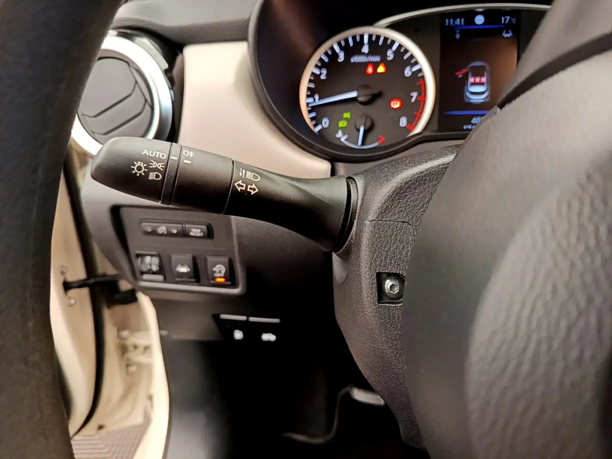 Gros plan sur le volant et le tableau de bord de la Nissan Micra blanche, avec commandes et affichages visibles.