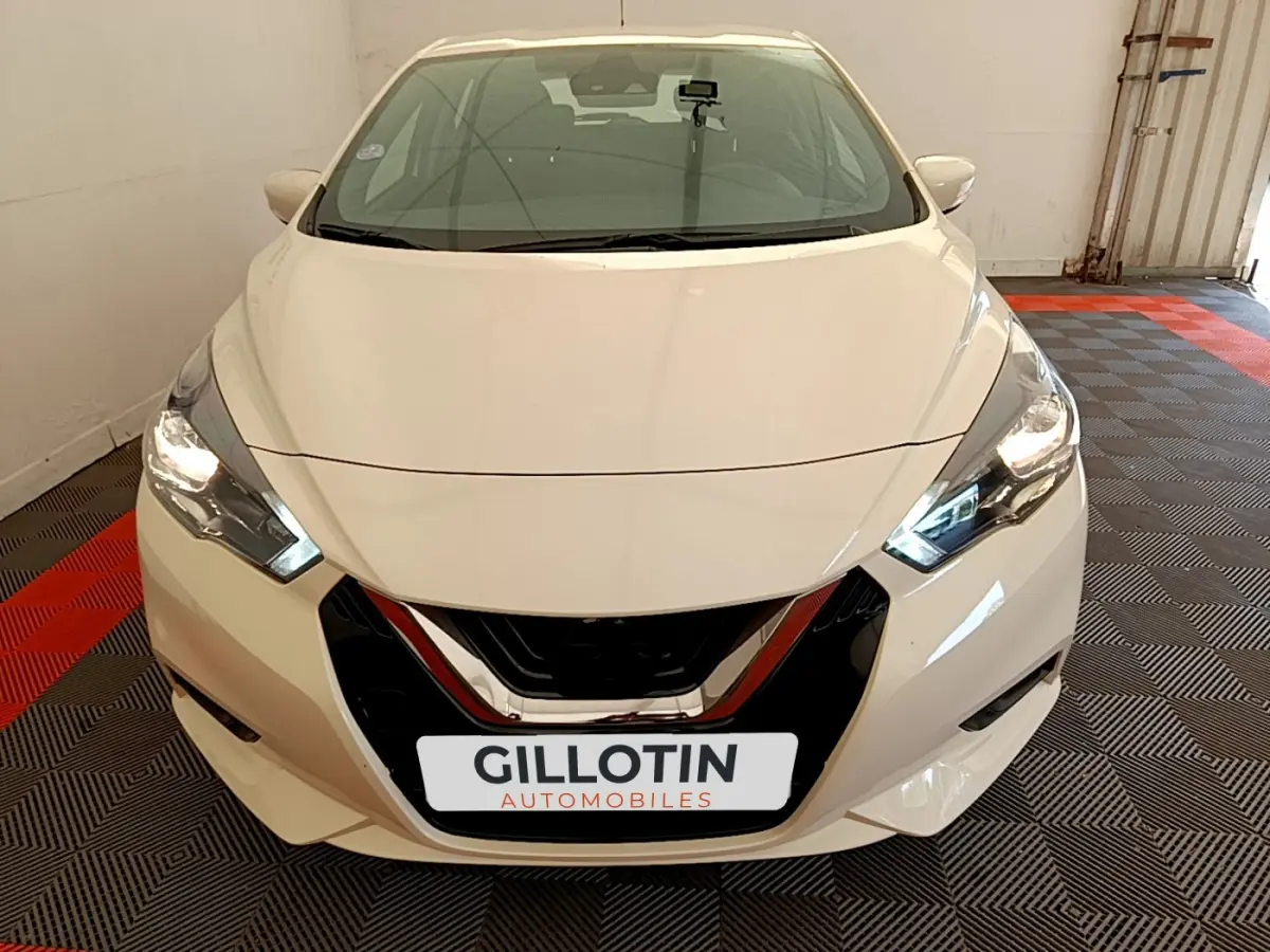 Vue de face d'une Nissan Micra blanche 2022 avec phares allumés et calandre noire brillante.