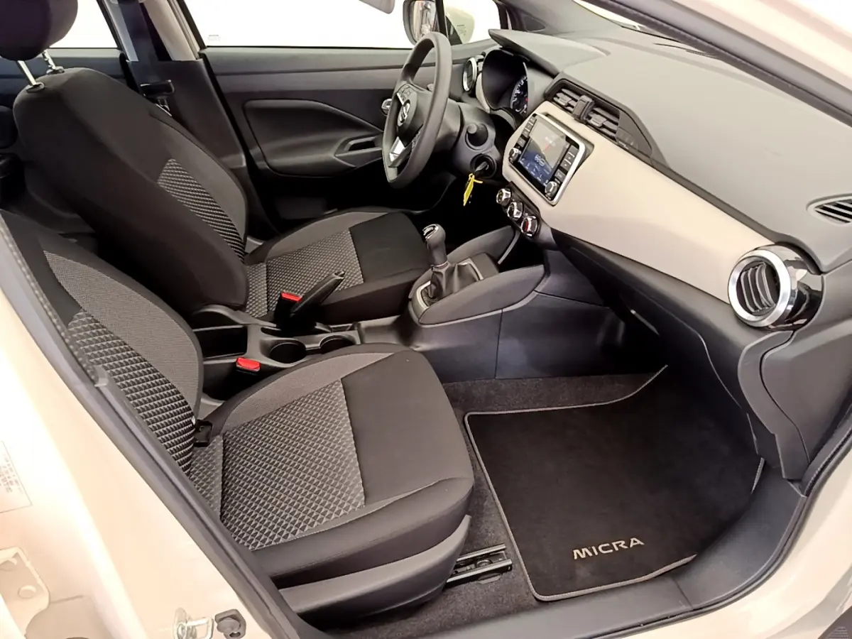 Intérieur avant droit de la Nissan Micra IG-T 92 Acenta 2022, sièges tissu gris et tableau de bord clair avec écran tactile.