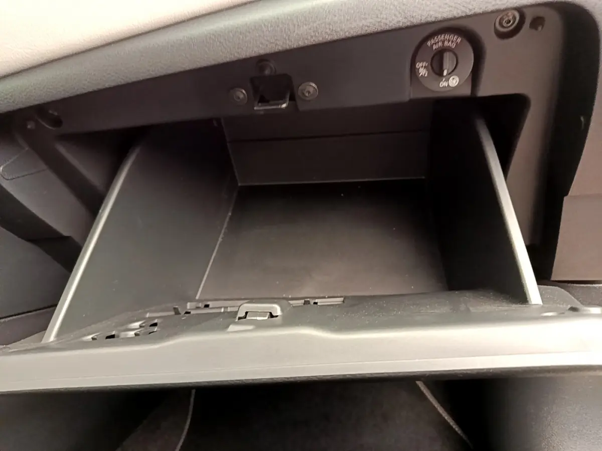 Gros plan sur la boîte à gants noire ouverte de la Nissan Micra IG-T 92 Acenta blanche, intérieur visible.