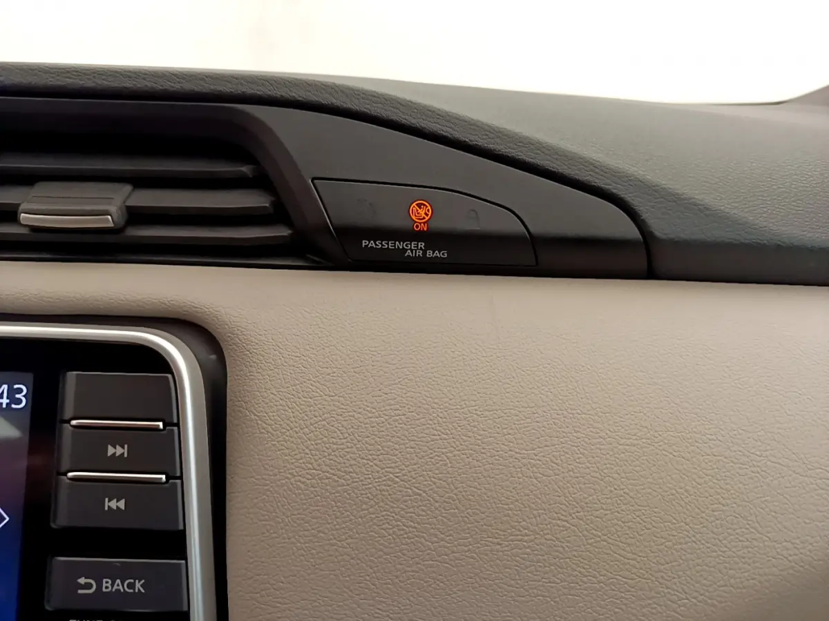 Détail du tableau de bord beige de Nissan Micra 2022 avec témoin airbag passager allumé en orange