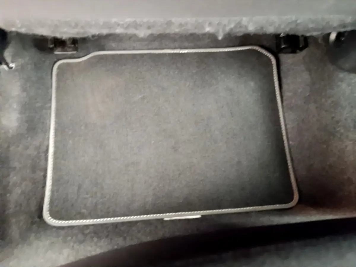 Vue rapprochée du coffre intérieur noir de la Nissan Micra IG-T 92 Acenta blanche, soulignant la moquette et le tapis.