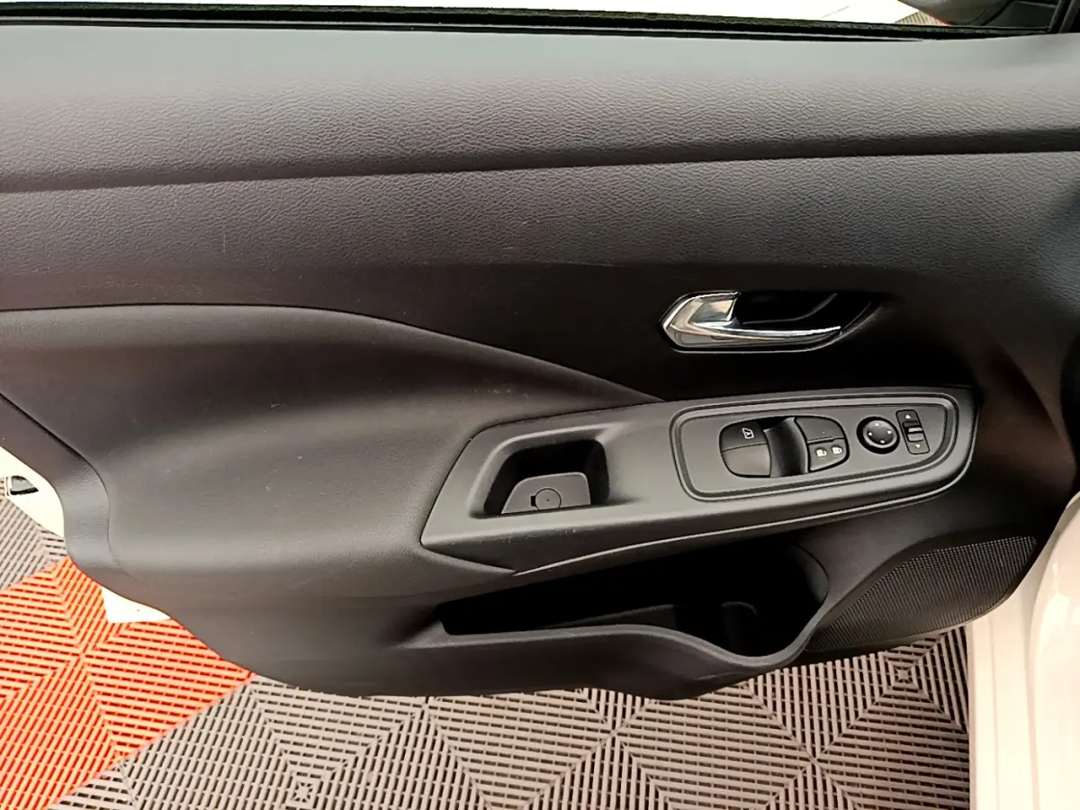 Gros plan sur la porte côté conducteur noire de la Nissan Micra IG-T 92 Acenta blanche avec commandes électriques des vitres.