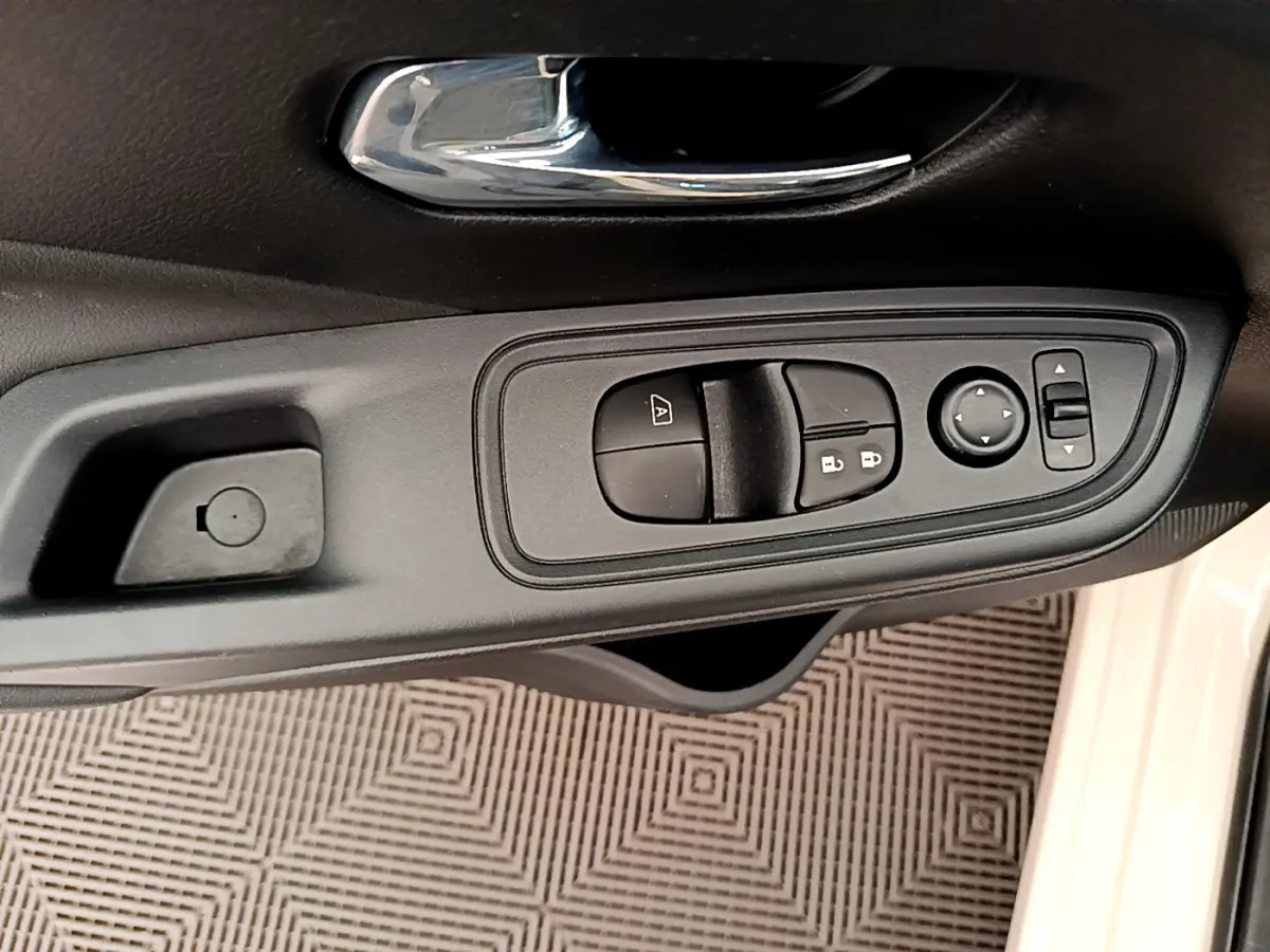 Gros plan sur la commande des vitres et rétroviseurs côté conducteur d'une Nissan Micra blanche 2022.