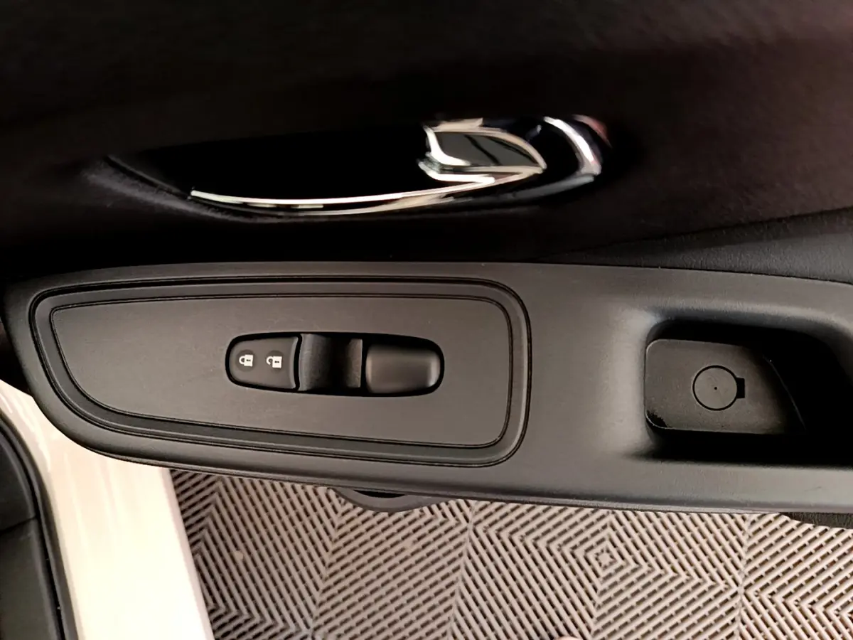 Poignée intérieure noire côté conducteur de la Nissan Micra IG-T 92 Acenta blanche, avec commandes de verrouillage.