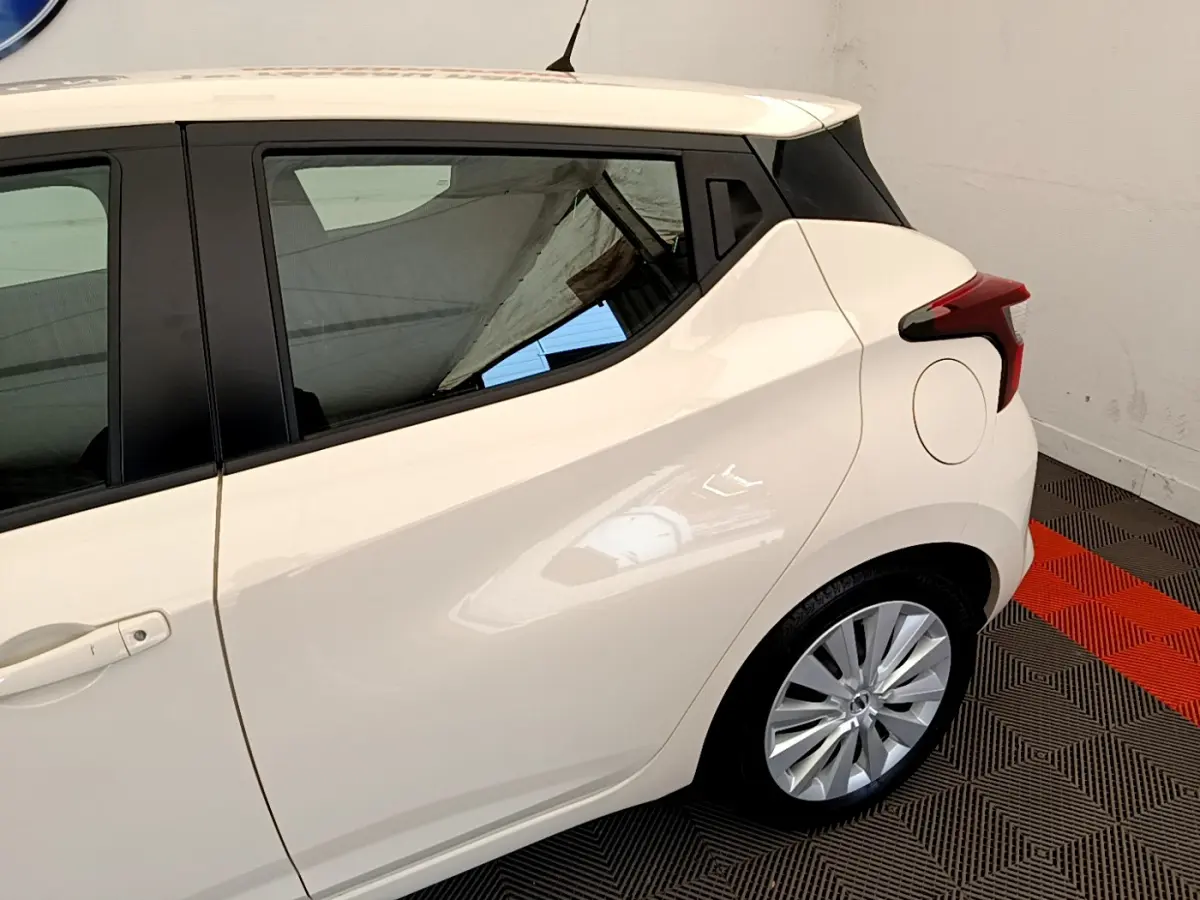 Vue côté gauche arrière d'une Nissan Micra blanche 2022 avec poignées intégrées et feux arrière anguleux.