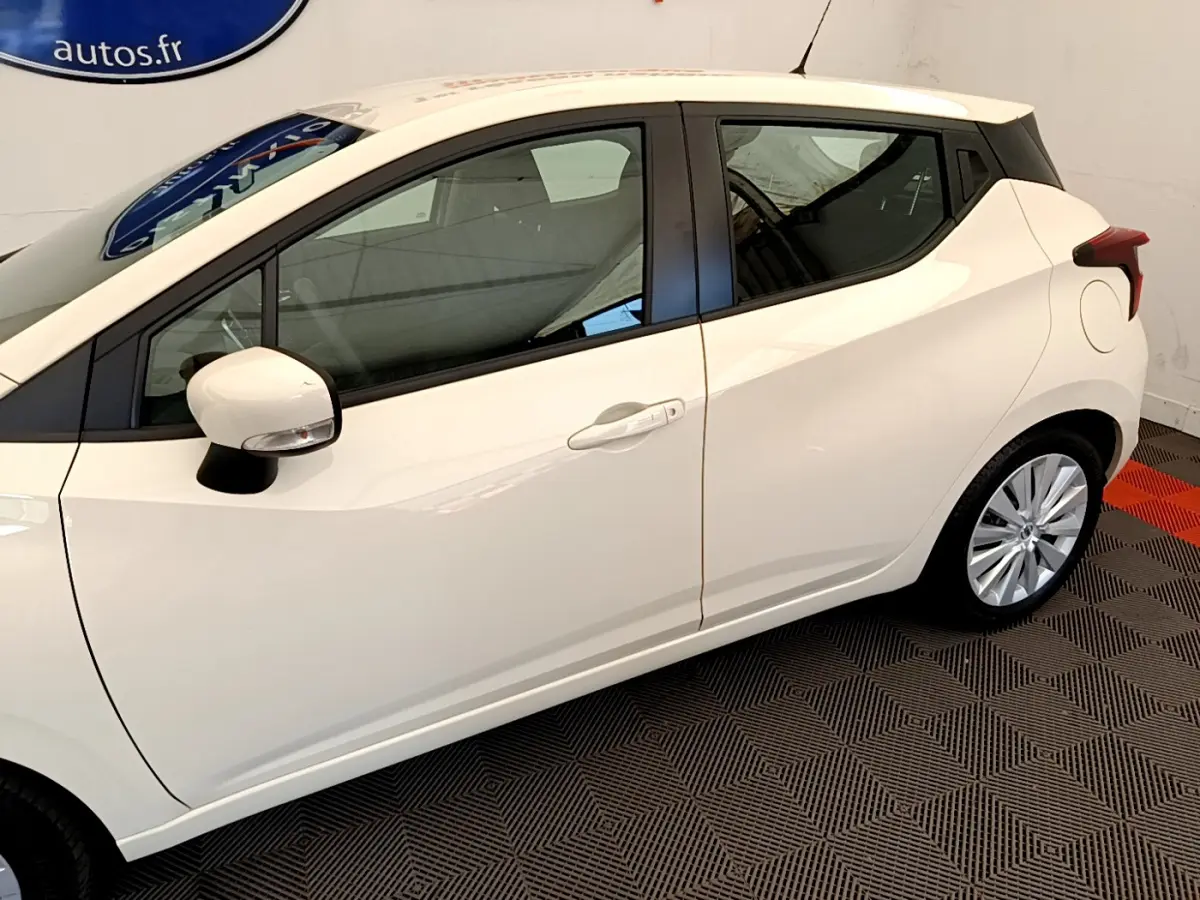 Vue latérale côté gauche d'une Nissan Micra IG-T 92 Acenta blanche avec jantes alliage et rétroviseur assorti.