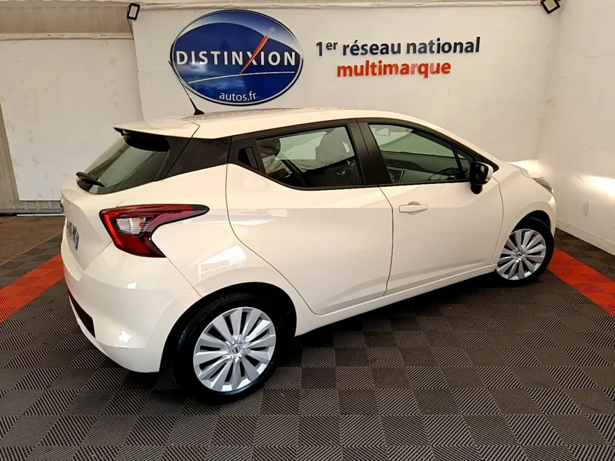 Nissan Micra IG-T 92 Acenta blanche vue de profil côté droit en intérieur avec jantes argentées et feux arrière distinctifs.