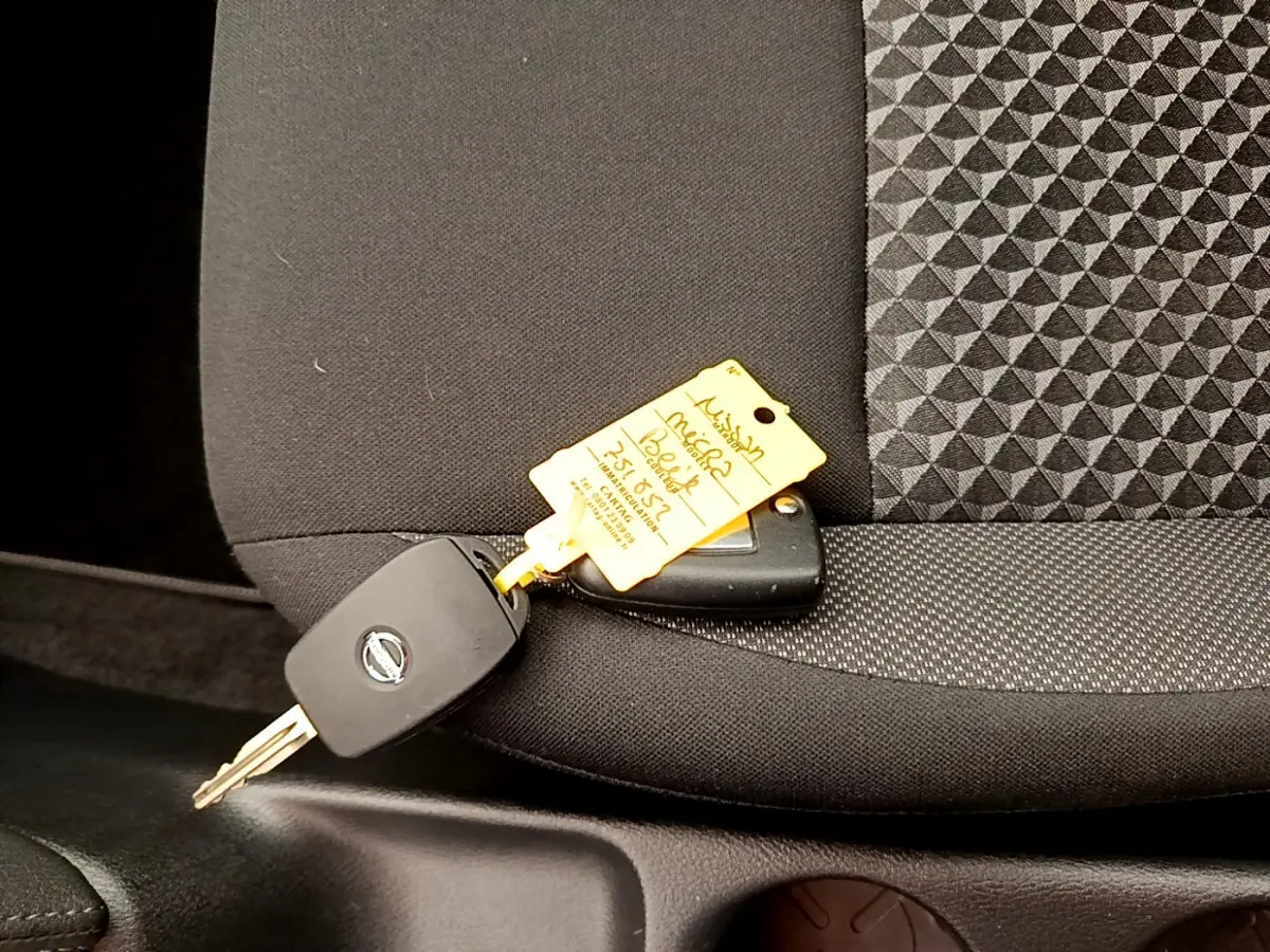 Clé de voiture Nissan posée sur un siège avant noir avec tissu à motifs géométriques à l'intérieur d'une Micra blanche 2022.