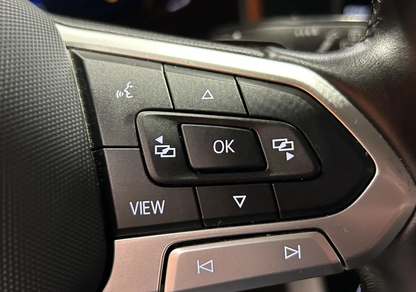 Gros plan sur les commandes multifonctions noires et argentées du volant de la Volkswagen Polo noire 2022.