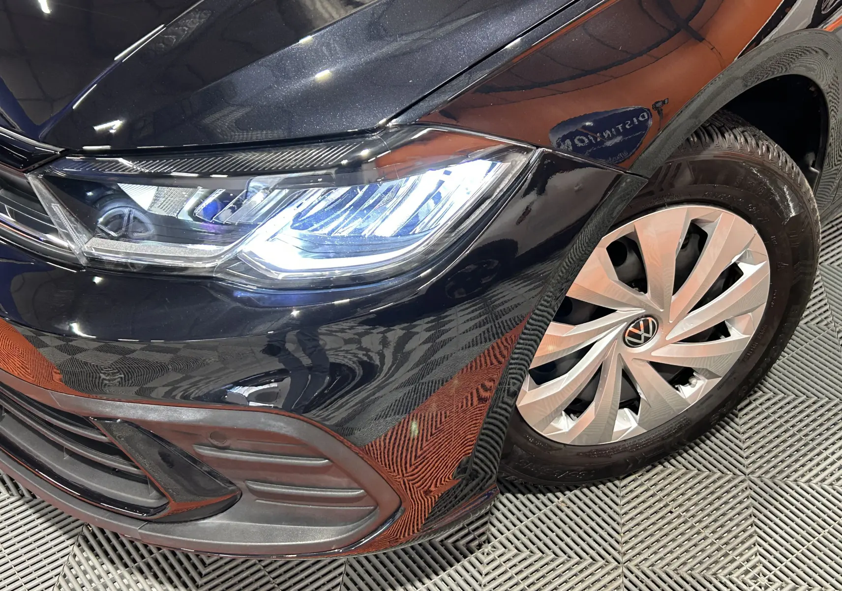 Gros plan sur l'avant droit noir brillant d'une Volkswagen Polo 2022, mettant en valeur le phare LED et la jante alliage.